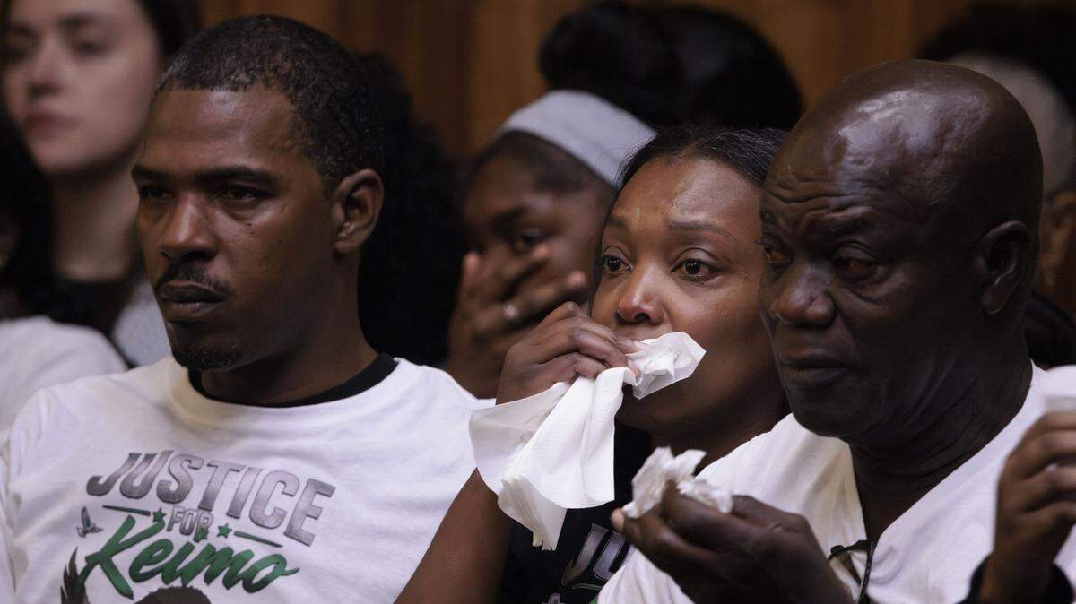 Nathalie Jean, center, mother of victim Yahkeim ‘Keimo’ Lollar, and his father, Darveed Lollar Sr., left, watch a video showing their son being stabbed. The video was shown at the sentencing hearing of Jahara Malik, not pictured, after she pleaded guilty to a manslaughter charge. The hearing was held Tuesday, May 5, 2026, at the Richard E. Gerstein Justice Building in Miami.